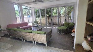 A spacious living area with a sofa, two chairs, and a bookshelf.