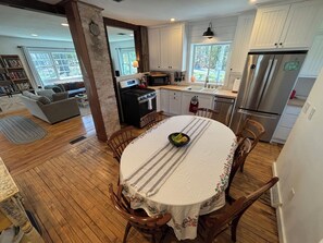 Una cocina con una mesa de comedor, sillas, un refrigerador y una estufa.