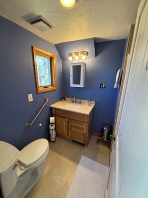 Un baño con inodoro, lavabo, tocador y ventana.