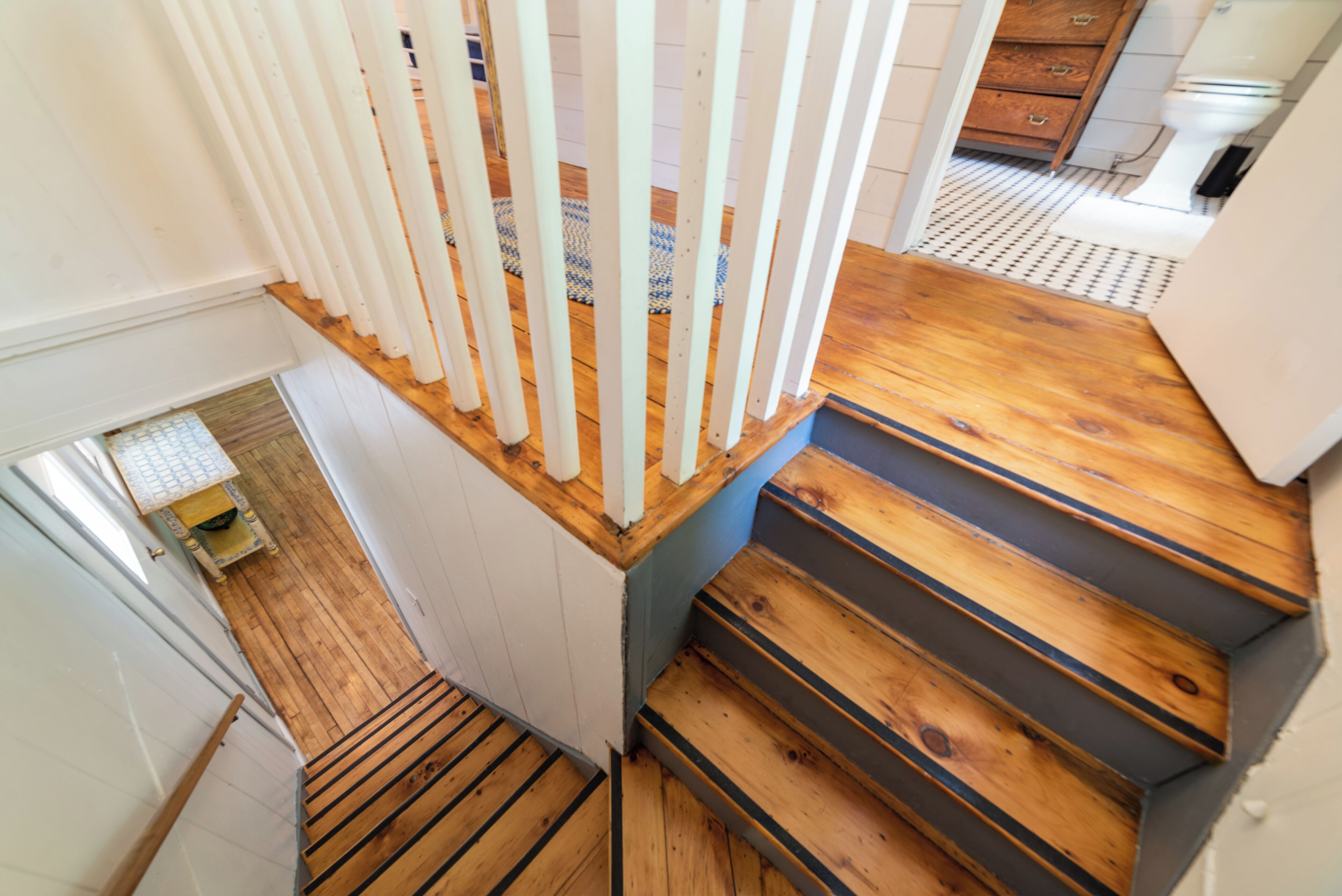 Una escalera de madera con barandillas blancas que conduce a un rellano en el segundo piso.