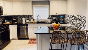 Una cocina moderna con armarios blancos, encimera negra y salpicadero de azulejos.