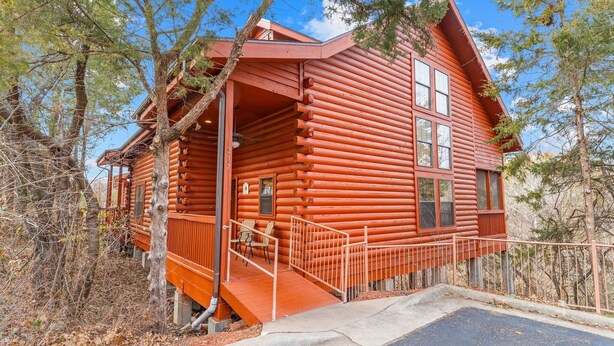 A log cabin with a porch, a staircase, and a view of the surrounding forest. - Walk-In 2BR Grand Mountain Cabin with Ozark Views | Sleeps 6 (Branson)