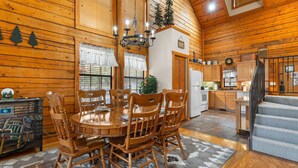 A wooden interior with a dining area, kitchen, and staircase. - Walk-In 2BR Grand Mountain Cabin with Ozark Views | Sleeps 6 (Branson)