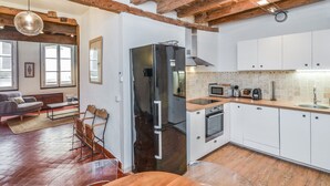 A modern kitchen with white cabinets, a stainless steel refrigerator, and a wooden dining table.