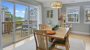 A dining area with a large table, chairs, and a hanging light fixture. - Make your summer memories here! (Wells)