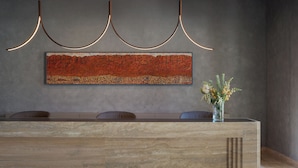 A reception area with a marble counter, three pendant lights, a large abstract painting, and a vase with flowers. - Garde Hotel and Warders Cottages (Fremantle)