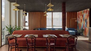 A modern restaurant with a long communal table, individual booths, and pendant lighting. - Garde Hotel and Warders Cottages (Fremantle)