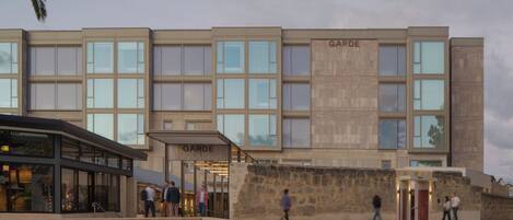 En moderne bygning med navnet 'GARDE' på facaden, med store vinduer og en stenvæg.