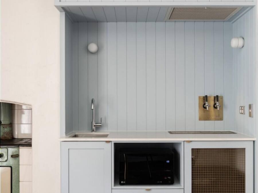 A compact kitchen with a built-in oven, a sink, and a ventilation hood.
