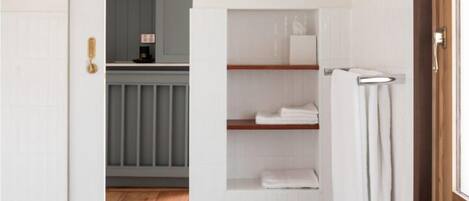 Une salle de bain moderne avec des carreaux blancs, un sol en marbre, une porte en bois et une vue sur un espace cuisine.
