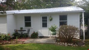 A single-story house with a front porch, a small table and chairs, and a potted plant.
