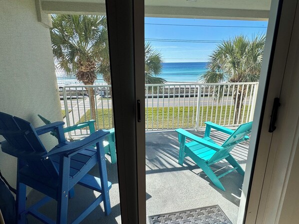 A balcony with turquoise chairs and a view of the ocean.