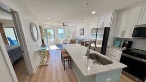 Una cocina moderna con una isla central, electrodomésticos de acero inoxidable y vistas al exterior.