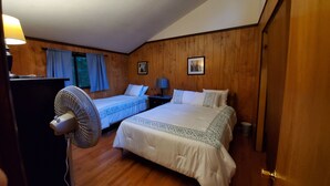 A hotel room with two beds, a desk with a lamp, a fan, and wooden walls. - House located in the heart of the Poconos and convenient to all!!!! (Pocono Pines)