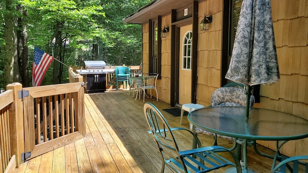 A wooden deck with a grill, outdoor seating, and an American flag. - House located in the heart of the Poconos and convenient to all!!!! (Pocono Pines)