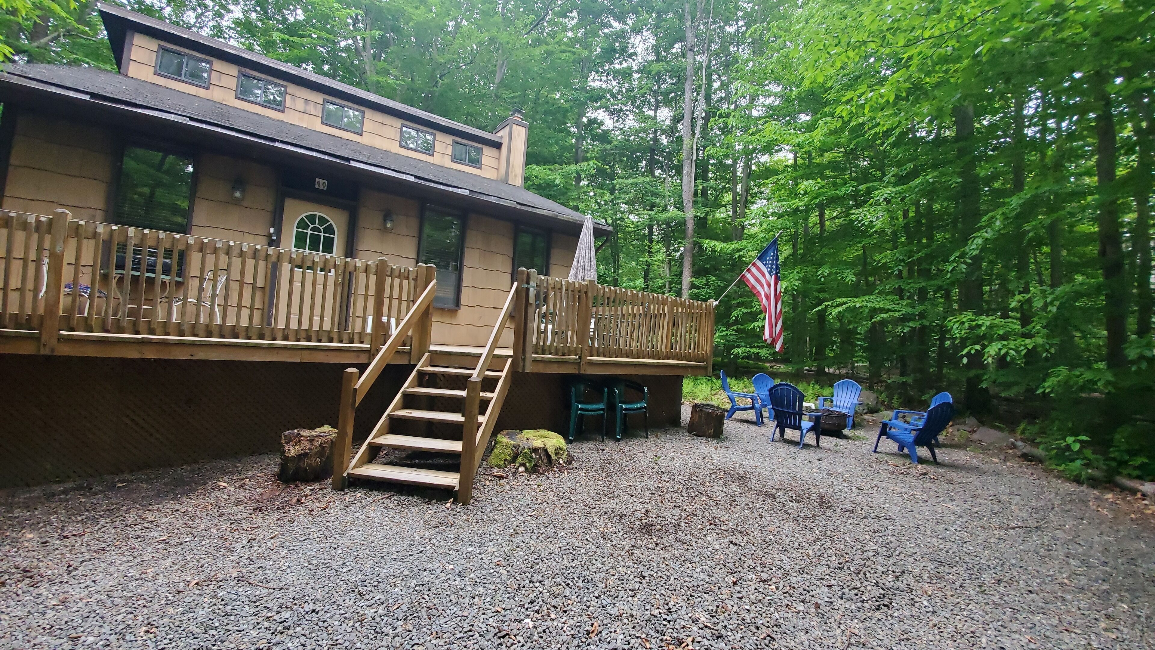 A cabin with a wooden deck, a staircase, and outdoor seating.