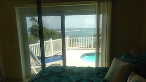 Un dormitorio con cama, vistas al océano y una piscina exterior.