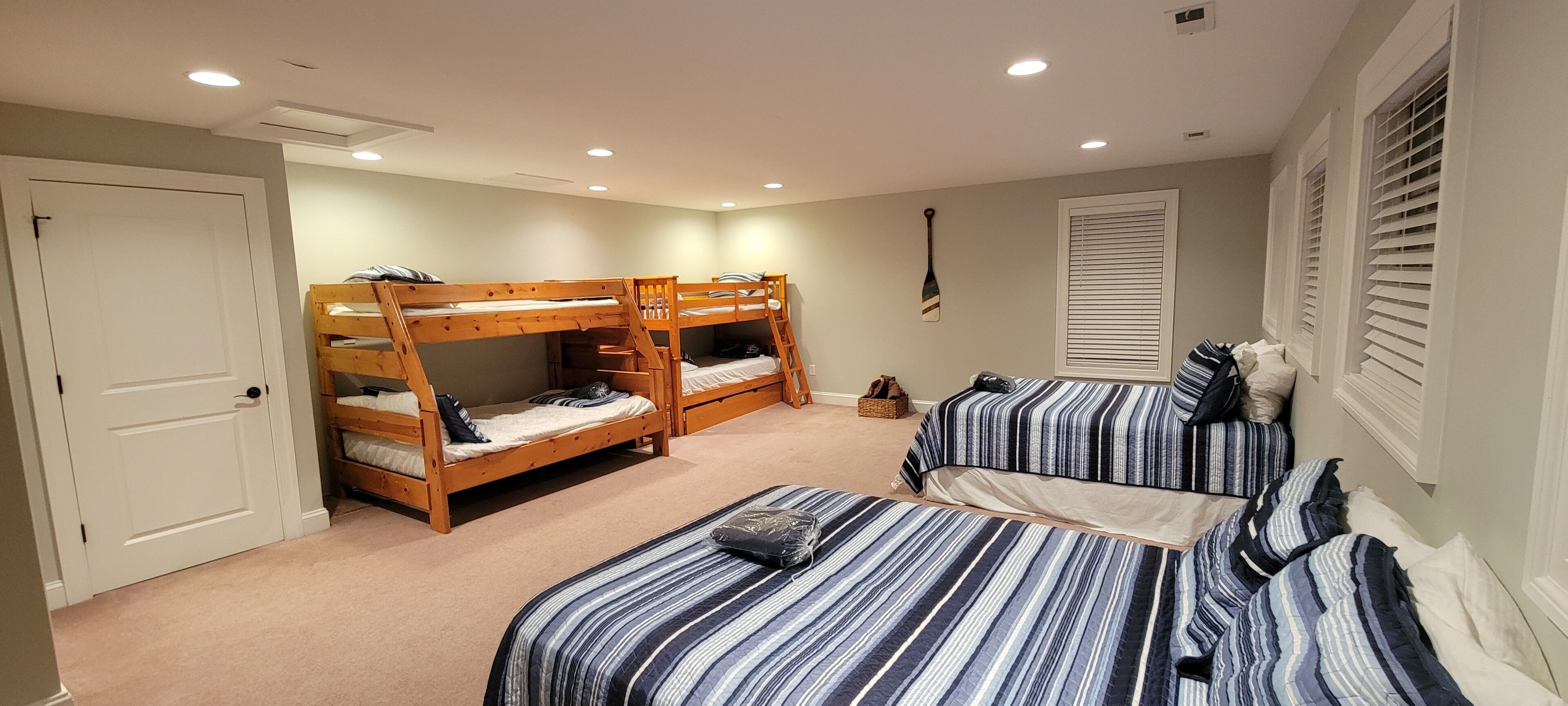 A bedroom with bunk beds and a single bed, carpeted floor, and a door.