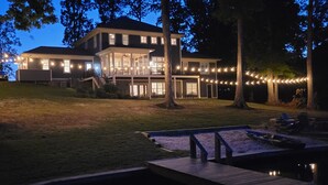 Une maison à deux étages avec une terrasse et des guirlandes lumineuses.