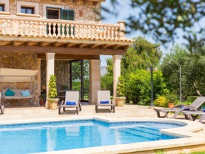 A pool area with lounge chairs, a pergola, and a stone building with a balcony. - Villa Lagoon. Lovely stone built Mallorcan finca with private pool. (Sa Pobla)