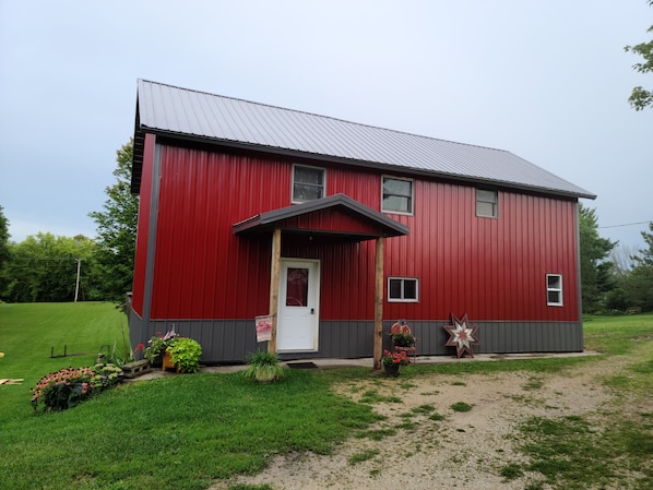 A red building with a white door and a small porch. - The Barn House Lodge (Spillville)