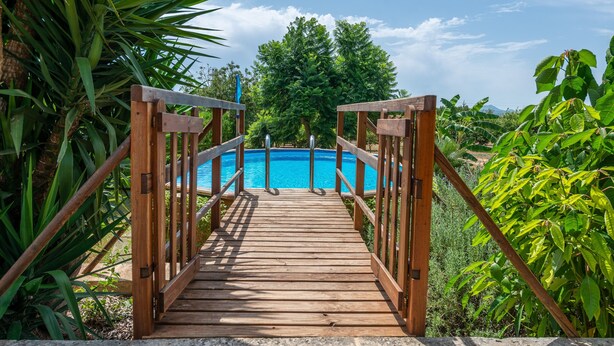 A wooden bridge leading to a pool surrounded by lush greenery. - SON LLORINGO - Beautiful villa with private above ground pool, a beautiful garden and view (Manacor)