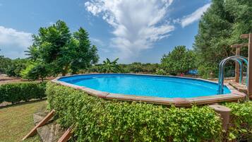 Relax by the serene pool surrounded by lush greenery and mature trees.
