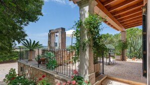 A courtyard with a stone fountain, potted plants, and a wooden pergola. - SON LLORINGO - Beautiful villa with private above ground pool, a beautiful garden and view (Manacor)