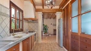 A kitchen with wooden cabinets, a tiled backsplash, and a central island. - SON LLORINGO - Beautiful villa with private above ground pool, a beautiful garden and view (Manacor)