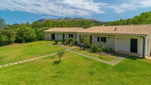 Una casa de dos pisos con techo de tejas, rodeada de un césped cuidado y un sendero de piedra que lleva a la entrada.
