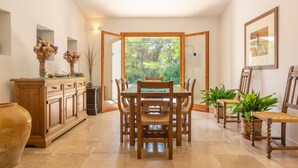 Un comedor con una mesa y sillas de madera, un armario y plantas en macetas.
