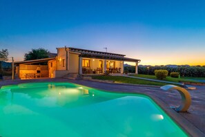 A house with a swimming pool, a covered patio, and a view of the mountains.