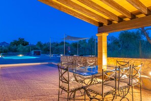 An outdoor patio with a table and chairs, a stone wall, and a pergola.