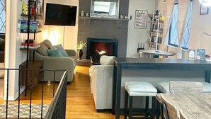 Un soggiorno moderno con camino, televisione e zona pranzo con sgabelli da bar.