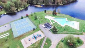 Vista aerea di un parco con campo da tennis, piscina e area giochi.