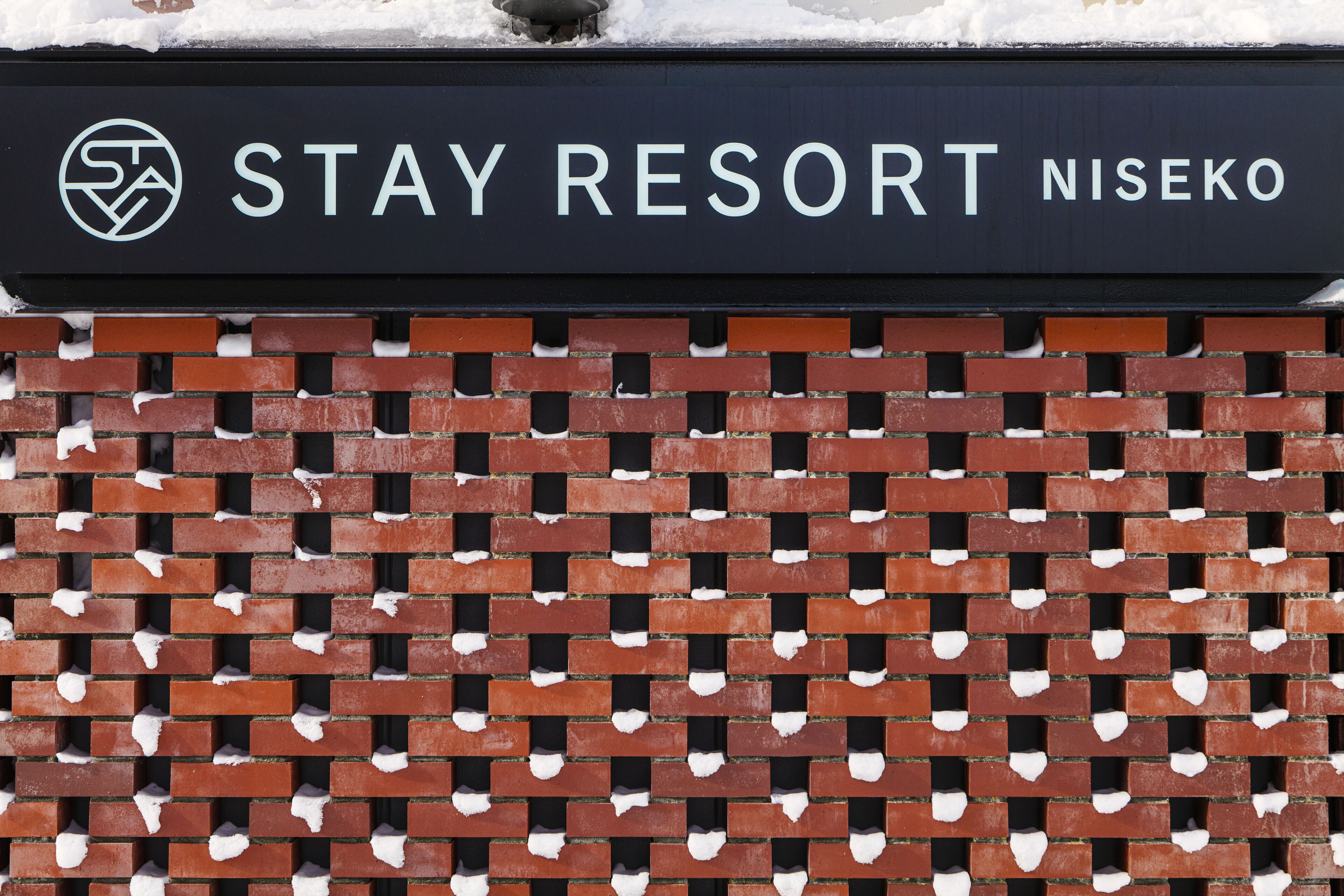 Un muro de ladrillo con un letrero que dice "STAY RESORT NISEKO".