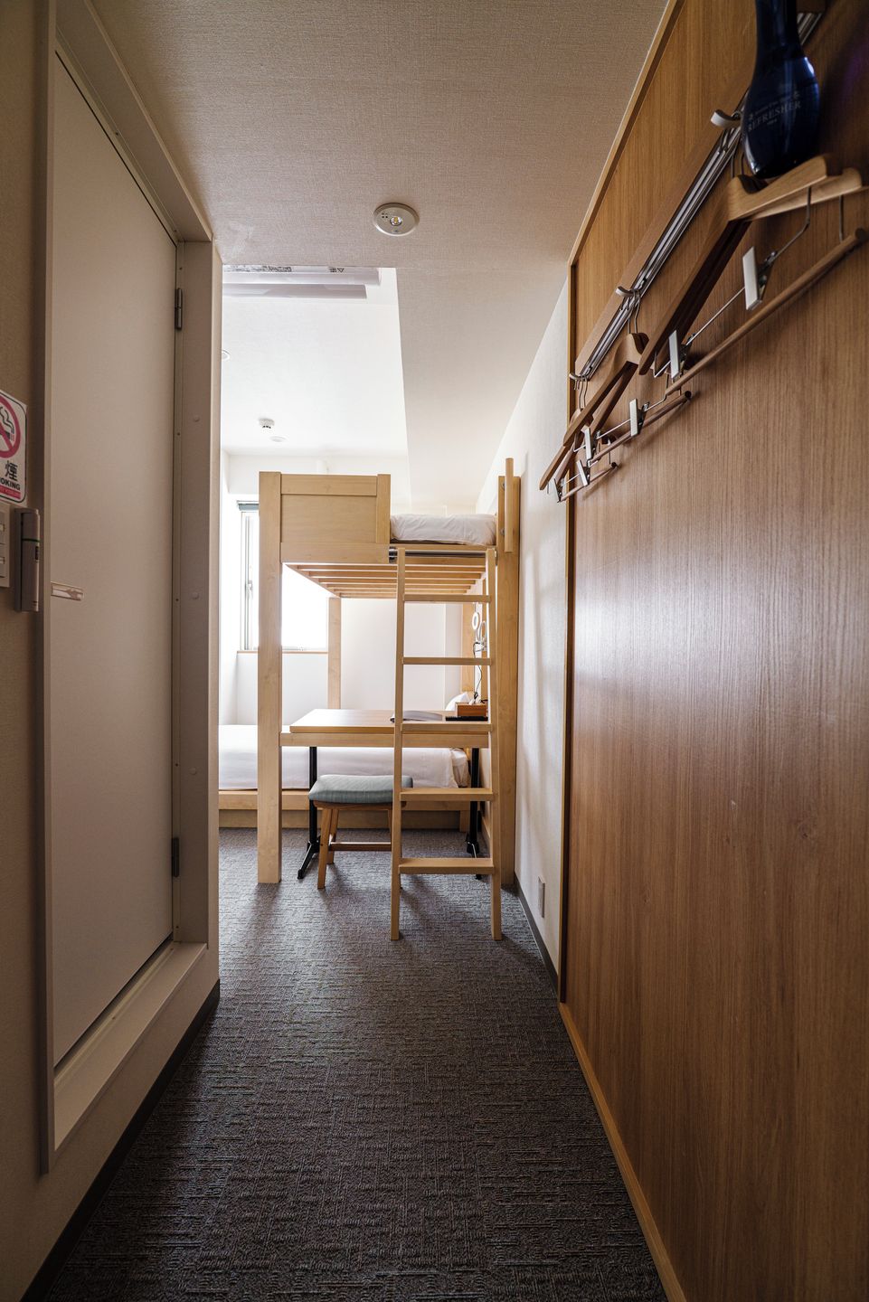 A room with a bunk bed, a desk, and a wardrobe.