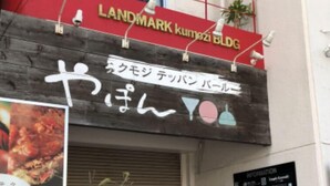 Un bâtiment avec une enseigne rouge et blanche sur laquelle on peut lire : « LANDMARK Kumozi BLDG. »