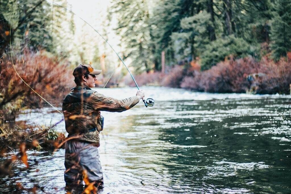 A person standing in a river, holding a fishing rod.