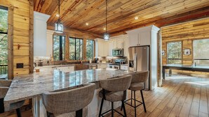 A spacious kitchen with a large island, wooden ceiling, and large windows. - Panoramic Views | Sauna · Hot Tub · Game Room (Broken Bow)