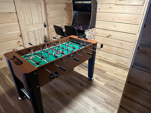 Una mesa de fútbol de mesa en una habitación con paredes y suelo de madera.