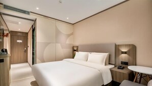 A modern hotel room with a large bed, bedside tables, a small round table, and a wardrobe. - Hanting Hotel (Guangzhou Feixiang Park Metro Station) (Guangzhou)
