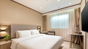 A modern hotel room with a large bed, a bedside table with a lamp, a small desk with a chair, and a TV on the wall. - Hanting Hotel (Guangzhou Feixiang Park Metro Station) (Guangzhou)