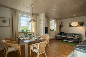 A dining area with wicker chairs, a wooden table set for four, and a hanging pendant light.