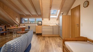 Une pièce compacte comprenant un lit en mezzanine, une kitchenette, un coin repas et une grande fenêtre avec vue.