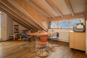 Une pièce avec un plafond en bois, une table à manger avec des chaises, un radiateur et une fenêtre donnant sur un beau paysage.