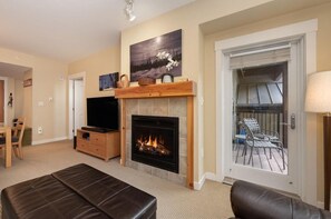A living room with a fireplace, a television, and a dining area.