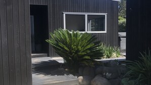A modern building with a dark exterior, a visible window, and a pathway leading to the entrance. - Luxury Home with pool/spa; close to beach/ 4 bedroom/ 2 bath. On golf course. (Whangamata)