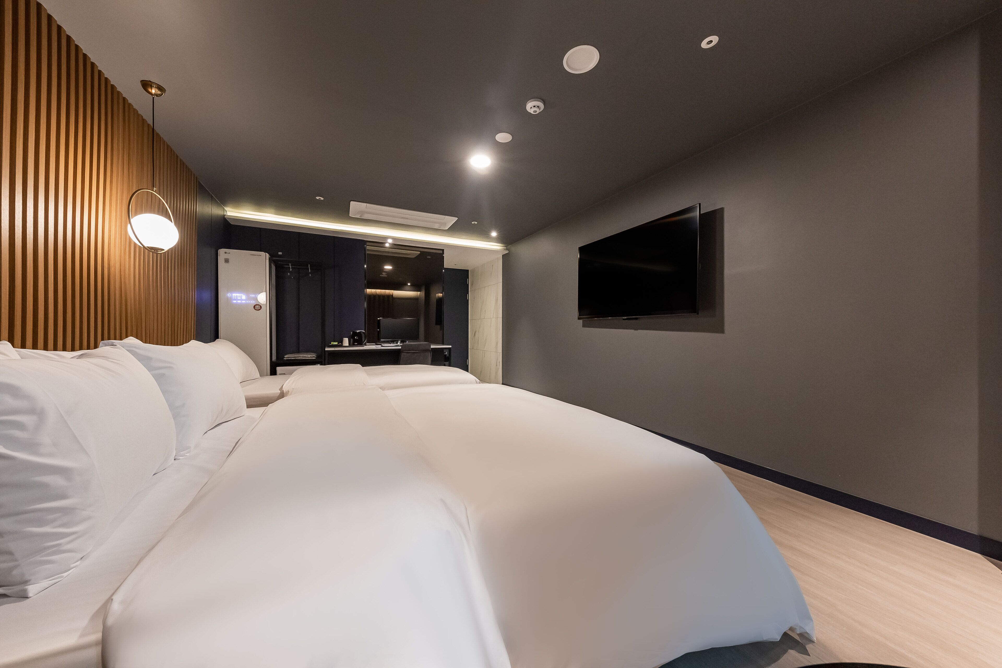 Ett modernt hotellrum med en stor säng, en platt-TV som är monterad på väggen och en väggpanel i trä på den vänstra väggen.