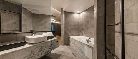 Un baño moderno con un espejo grande, dos lavabos, una bañera y paredes con azulejos.